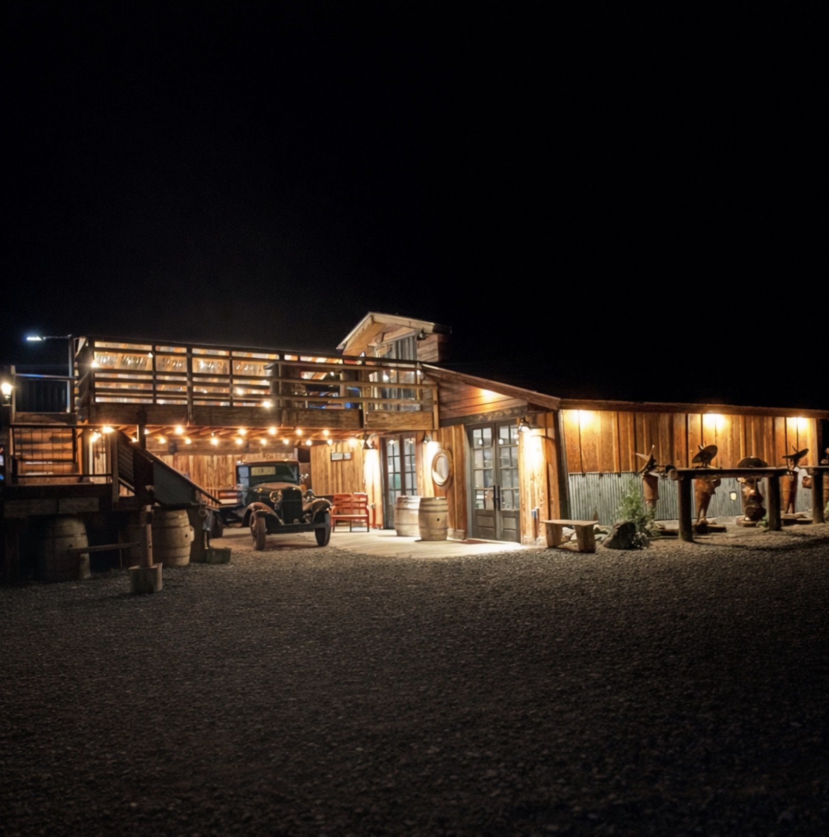 The Bourbon Barn lit up at night - string lights along the deck and the 1932 Ford out front
