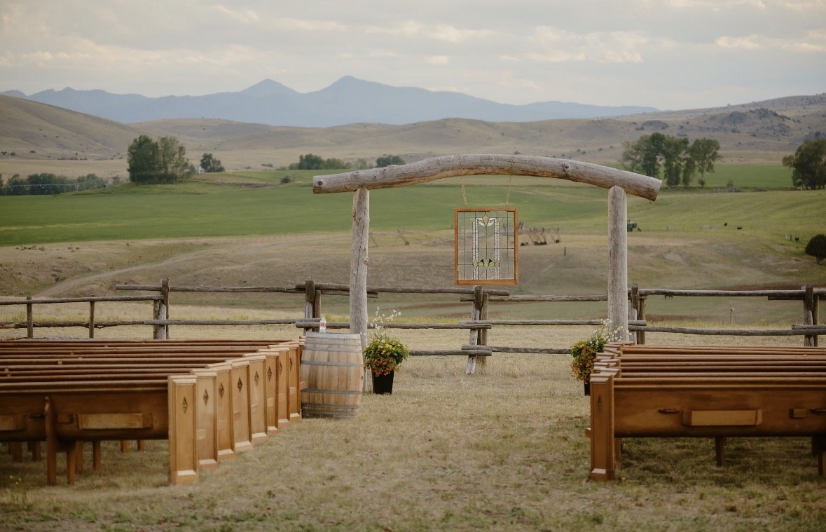 Handcrafted wooden pews and the handmade ceremony arch with its stained-glass window in the Ceremony Meadow